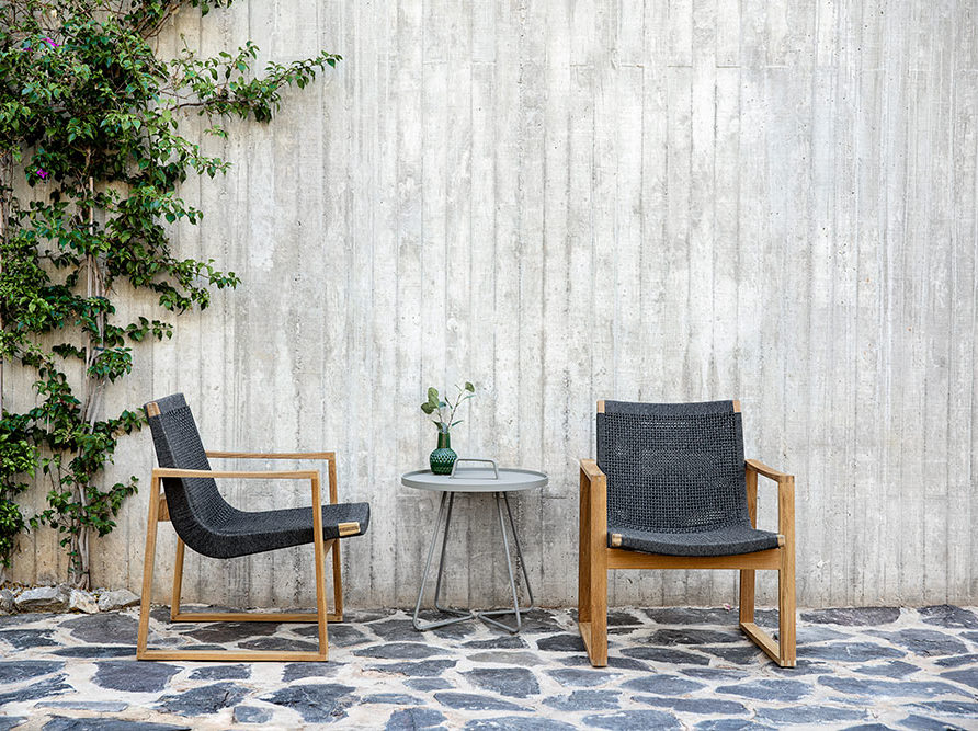 Outdoor-Möbel vor einer Betonwand: kleiner, runder Tisch und 2 Stühle
