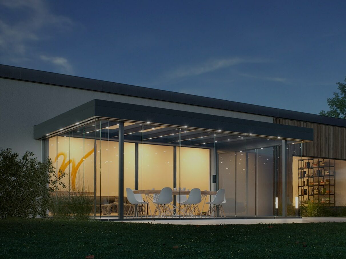 Terrassendach Diafano Lounge aus Alu und Glas mit gläsernen Seitenwänden als Sommergarten in Ansbach bei Nacht.