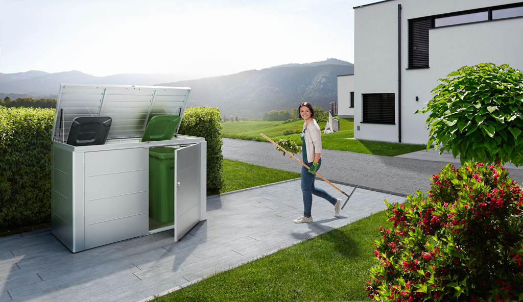 Biohort Mülltonnenbox HighBoard mit geöffnetem Deckel in einem Garten in Bayern.