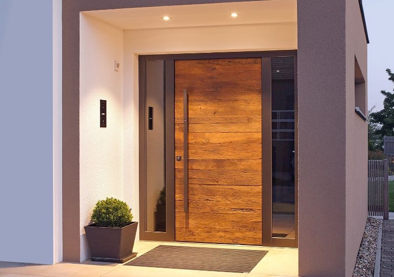 Moderne Holzhaustür bei Kutz mit Kombination aus natürlicher Holzoberfläche und dunkler Türfläche sowie verglasten Seitenteilen.